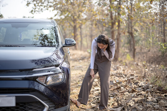 A frustrated girl near her damaged or punctured car