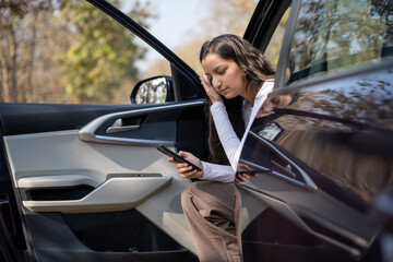 young woman driving in car and checking her phone network, annoyed by navigation gps system or bad...