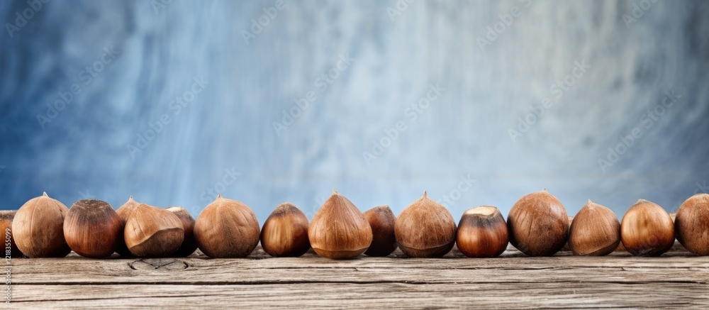 Poster hazelnuts lined on a rustic wooden surface with a textured blue background, showcasing natural earth