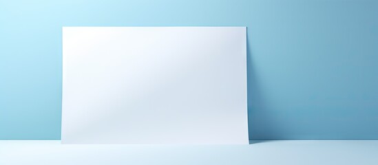 Naklejka premium Blank white paper positioned on a soft blue background with shadow effects creating depth and an invitingly simple layout for copying space.
