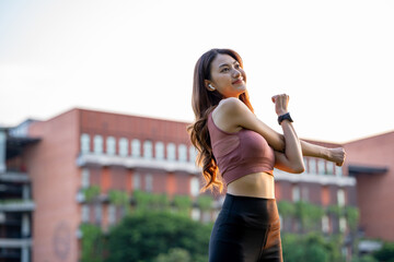 Healthy and fit asian woman wearing sportswear warming up in the park at sunrise. Confident young...