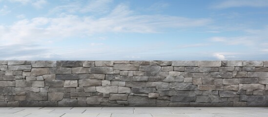 Gray stone wall with a clear blue sky in the background, showcasing a horizon line that adds depth to the rustic textured surface.