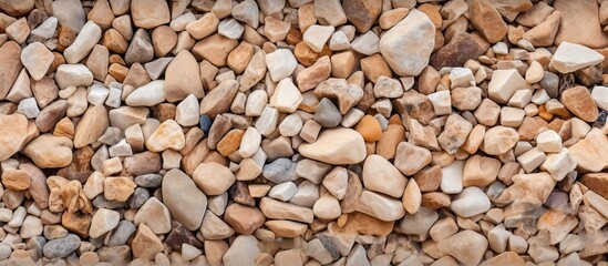 Naklejka premium Close up of mixed beige and brown sandstone gravel stones in various shapes and sizes with textured surface and ample copy space in the center