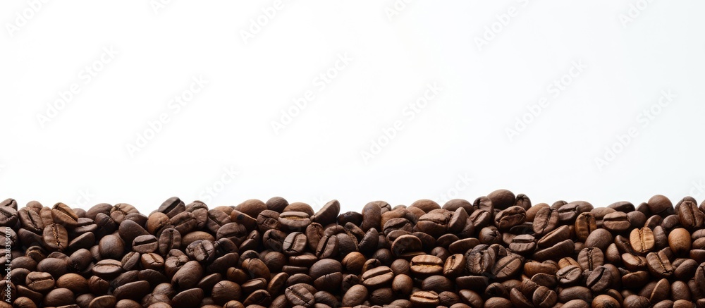 Poster Coffee beans arranged in a horizontal line along the bottom of a soft white background with shallow depth of field creating ample copy space.