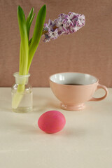 One pink easter egg with a purple hyacinth and teacup.