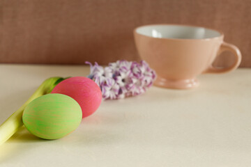 two colorful easter eggs with hyacinth and teacup