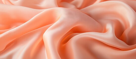 Obraz premium Peach silk fabric elegantly draped showcasing smooth texture and soft sheen ideal for fashion design and custom clothing production.