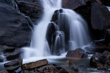 Obraz premium Waterfall flowing over rocks in mountainous area