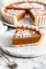 Sea Salt Butterscotch Tart Delicious salted caramel tart slice on marble plate in elegant dessert setting
