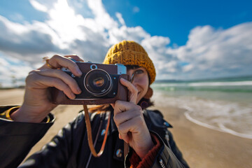 Young girl taking photo outdoors with film camera. Young girl tourist having fun on beach.