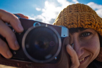 Young girl taking photo outdoors with film camera. Young girl tourist having fun on beach.