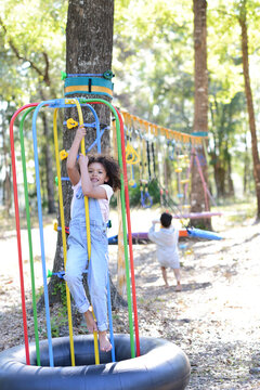 Smiling child climbing colorful poles on a play structure in a f