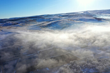 Aerial view of misty countryside hills at wintertime, morning fog above