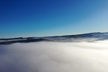 Aerial view of fog blankets during a bright winter morning under a clear blue sky