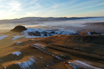 Flying over snowy winter hills in sunset lights