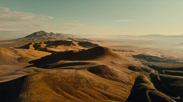 4K Aerial drone, views from Winnemucca Mountain, Nevada. Sunrise on yellow prairie, rolling hills. Golden hues of the arid land contrast with the blue sky, stretching into the horizon