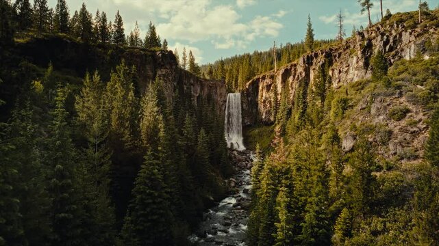 4k Aerial drone toward Tumalo Falls, Oregon. Waterfall nestled in a lush forest. Rushing water tumbles over a rocky cliff, surrounded by evergreens. The rugged wilderness of Deschutes National Forest.