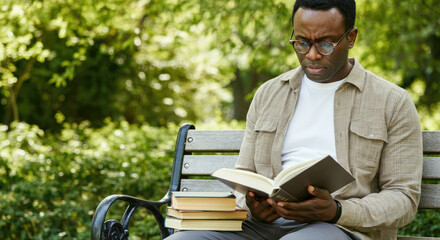 Fototapeta premium African American man reading book on park bench