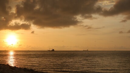 Low orange sunset in dramatic clouds over ocean in Indonesia