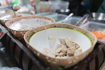 Slices of Thai pork sausage displayed in a decorative bowl at a salad stall.