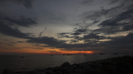 Low orange sunset in dramatic clouds over ocean in Indonesia