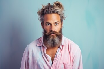 Obraz premium A man with a beard and a pink shirt is standing in front of a blue wall