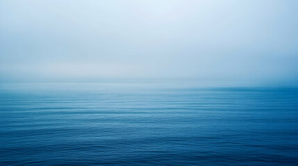 Obraz premium Serene ocean view on a misty morning, subtle waves, tranquil blue tones, calming minimalist seascape.