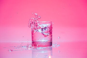 ice cube falling into glass of water with splash 