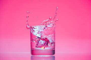 ice cube falling into glass of water with splash 