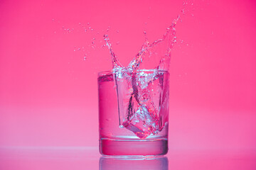 ice cube falling into glass of water with splash 