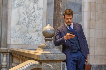 businessman with phone and briefcase checking his messages