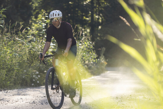 Solo biker on a dirt trail in a forest, exploring fitness and nature.