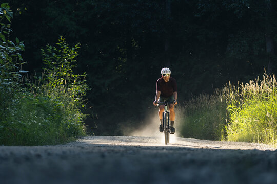 Solo biker on a dirt trail in a forest, exploring fitness and nature.