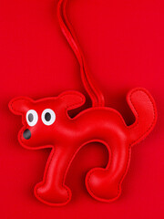 close up of leather red dog keychain with big funny eyes on  red  background