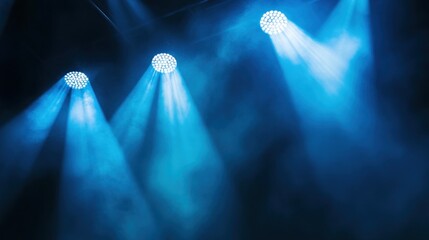 Three blue stage lights shining through smoke.