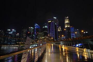 Fototapeta premium Marina Bay Sands lights up Singapore’s skyline at night with its glowing towers and rooftop, showcasing stunning modern architecture above the shimmering Marina Bay. 