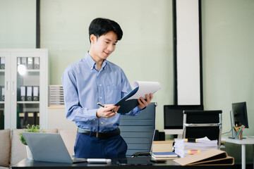 Young business man working at office with laptop, tablet and taking notes