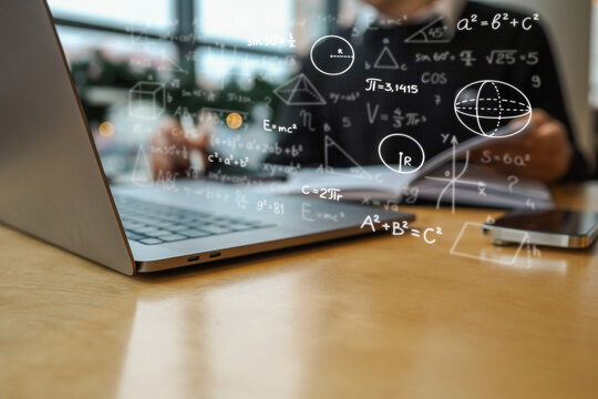 Laptop with mathematical formulas and geometric shapes overlaid in focus, with blurred background showing person holding notebook. Scene represents education, learning, or science - Powered by Adobe