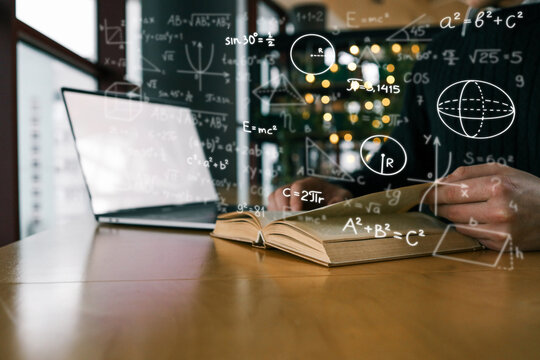 An open book on wooden desk surrounded by floating mathematical formulas, with laptop in background. Scene represents education, science, and academic study in modern environment.