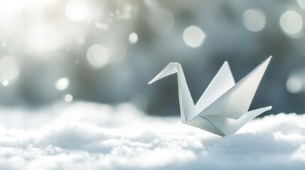 White origami crane rests delicately on snow with soft sunlight illuminating the scene