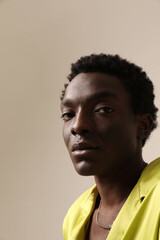 Obraz premium Headshot portrait of African American man wears yellow shirt posing over light background. 