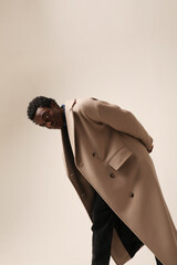Headshot portrait of young African American man wears winter coat posing over light background. 