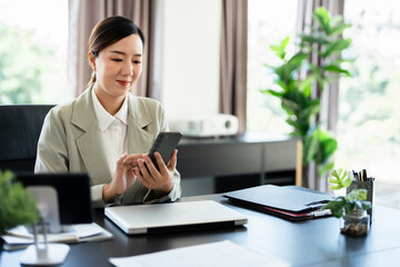 Busy professional middle aged business woman using mobile phone working in office. Smiling mature businesswoman executive holding cell at desk. Happy female worker making bank payments on smartphone.