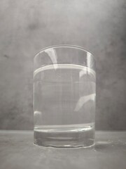 Clear glass of still water sits on a gray surface, reflecting the light in prague, czechia World Water Day copy space