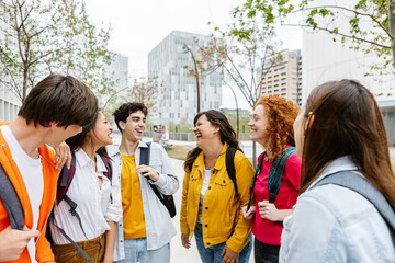 Young group of multiracial teenage students laughing and hanging out at high school campus. Youth and education lifestyle concept