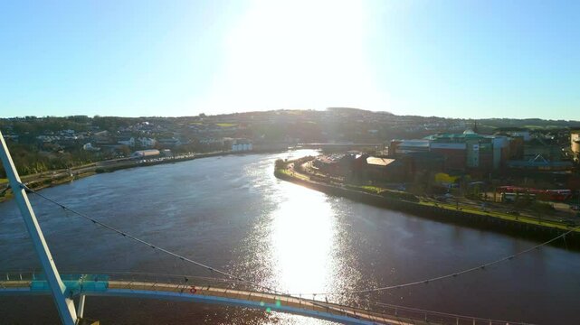 Wide aerial of The Peace Bridge and River Foyle in Derry-Londonderry on a sunny day. The camera reverses to reveal the Peace Bridge. Filmed in 4K, 60fps and with Rec709 color.