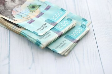 Big amount of ukrainian new one hundred hryvnia money bills with modern design on white wooden table. Financial concept, business