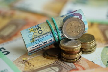 Roll of euro currency money bills and many euro cents on banknotes of european union