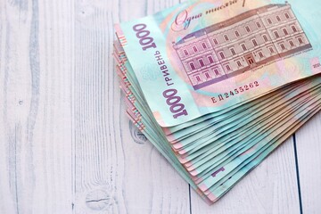 Big amount of ukrainian new one hundred hryvnia money bills with modern design on white wooden table. Financial concept, business