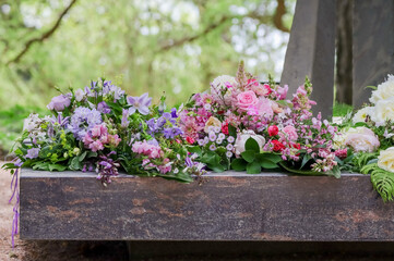 Several different grave bouquets on the memorial stone in the memorial grove of the Hietaniemi cemetery in Helsinki.